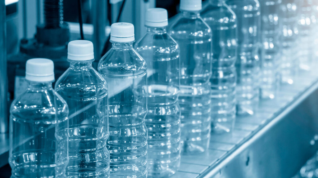 Botellas de PET en línea de producción con iluminación fría.